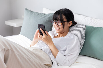ベットでスマホを操作する女性　A woman operating a smartphone