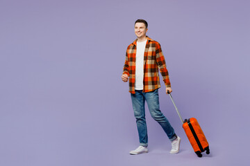 Traveler man wears shirt casual clothes hold suitcase walking going isolated on plain pastel purple...