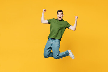 Full body young overjoyed excited cool happy man he wears green t-shirt casual clothes jump high do winner gesture clench fist isolated on plain yellow background studio portrait. Lifestyle concept.