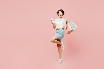 Full body side view overjoyed excited young woman wears casual clothes hold shopping paper package bags look camera isolated on plain pink color background studio. Black Friday sale buy day concept.