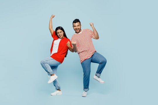 Full Body Young Couple Two Friends Family Indian Man Woman Wear Red Casual Clothes T-shirts Together Do Winner Gesture Celebrate Clenching Fists Say Yes Isolated On Plain Blue Cyan Color Background