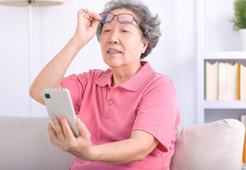 Presbyopia, senior asian woman holding eyeglasses having problem with vision problem trying to read...