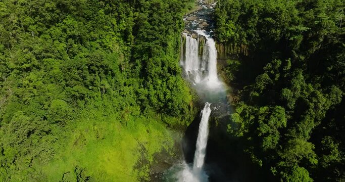 Aerial drone of jungle waterfall in a tropical forest surrounded by green vegetation. Limunsudan Falls. Mindanao, Philippines.