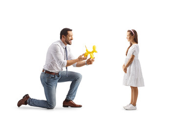 Profile shot of a man kneeling and showing a dog shaped balloon to a girl
