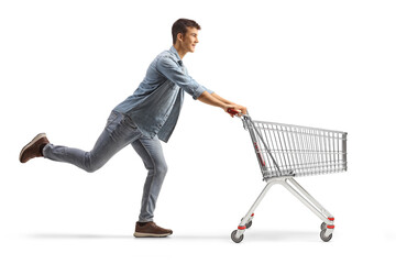 Full length profile shot of a male teenager running with an empty shopping cart