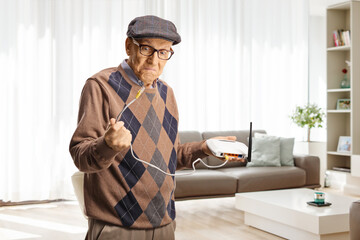 Irritated older man holding a router cable at home