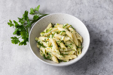 Penne pasta with zucchini, cream cheese and herbs on a gray textured background, top view. Vegetarian food, homemade healthy food