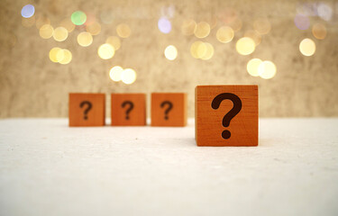 Cube with question mark on white table and bokeh light background. Space for text