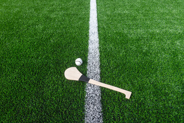 Fototapeta Hurling bat and sloitar on green grass. Horizontal sport theme poster, greeting cards, headers, website and app obraz