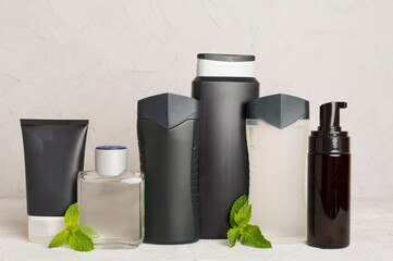 Men cosmetic bottles with mint leaves on table