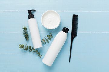 Professional hair care products with comb on color background, top view