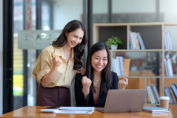 Two Asian businesswoman is excited and delighted achieved goal with laptop computer at office.