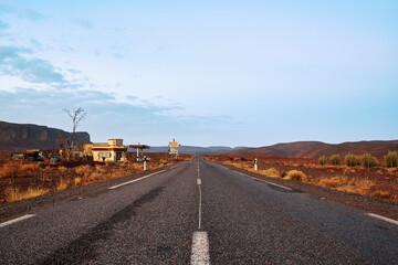 road to nowhere in the desert, with old gas station on the left 
