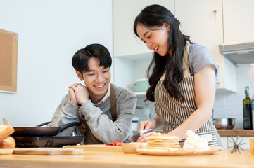 A lovely Asian couple enjoys making pancakes in the kitchen together. cooking date