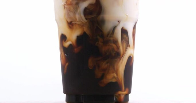 4K footage Front view SLO MO, Pouring freshly brewed americano coffee into a glass of water with ice on a white background.