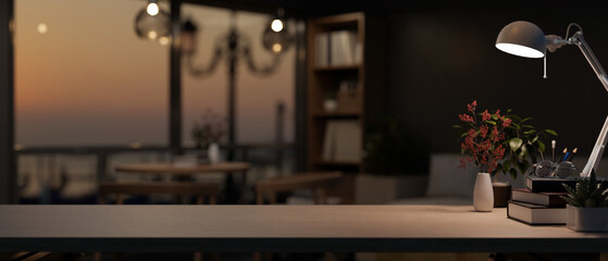 Copy space on a table with a table lamp and accessories in a dark, modern living room in the evening