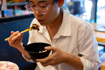 Young woman sitting and eating Japanese style hot pot shabu shabu