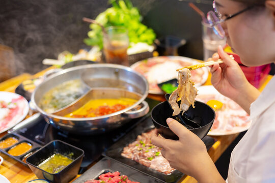 Young woman sitting and eating Japanese style hot pot shabu shabu