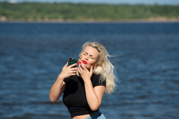 a girl corrects her makeup in nature by the river