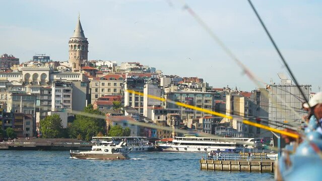 Blurred fishermen fishing rods on the bridge across the Golden Horn strait with Galata Tower in the background. Top places to visit in Istanbul.