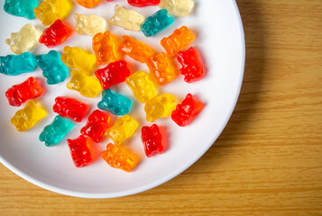 Sweet jelly bear candy on a white plate with a wood pattern background