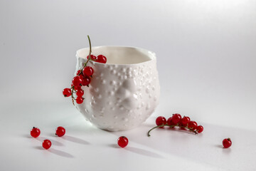 Porcelain white cup with red currants on a white background