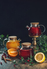 various teapots with herbal and fruit tea on black background.