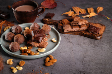 Cocoa in a clay mug, chocolate pieces and nuts on a dark background