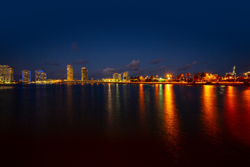 Fototapeta na wymiar Miami city skyline panorama at night skyscrapers and bridge over sea with reflection