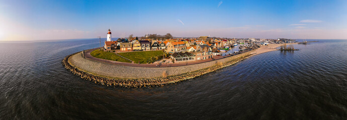 Urk Flevoland Netherlands sunset at the lighthouse and harbor of Urk Holland. Traditional Fishing Village Urk. Beautiful sunset during the evening, drone aerial view - obrazy, fototapety, plakaty