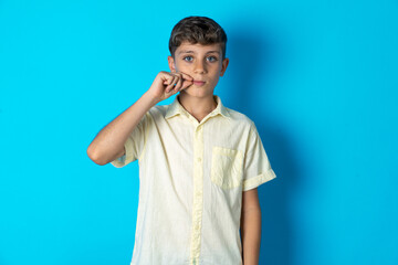 Beautiful kid boy wearing casual shirt mouth and lips shut as zip with fingers. Secret and silent,...