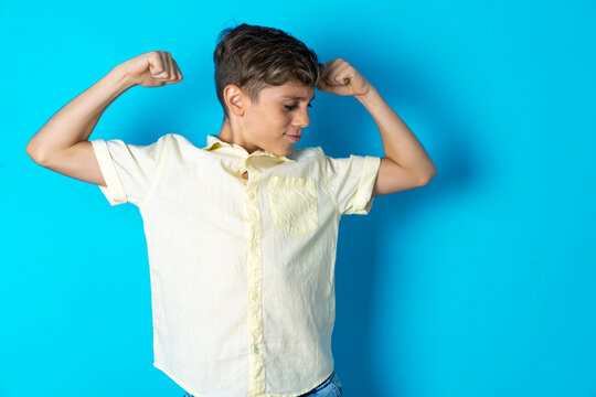 Beautiful Kid Boy Wearing Casual Shirt Showing Arms Muscles Smiling Proud. Fitness Concept.