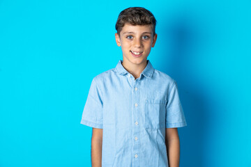 Fototapeta premium Beautiful kid boy wearing casual blue shirt with nice beaming smile pleased expression. Positive emotions concept