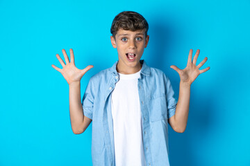 Delighted positive Beautiful kid boy wearing  casual clothes opens mouth  and arms palms up after...