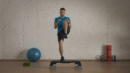 Closeup shot. Man fitness trainer in sportswear doing high knee jumps on step board exercise.