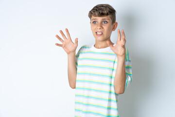 Beautiful kid boy wearing striped casual t-shirt afraid and terrified with fear expression stop gesture with hands, shouting in shock. Panic concept.