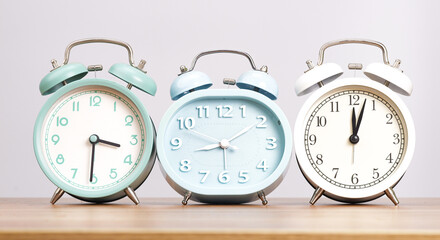 Three alarm clocks are placed on a table on a white background.
