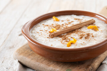 Arroz con leche. Rice pudding with cinnamon in clay bowl on wooden table