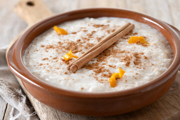 Arroz con leche. Rice pudding with cinnamon in clay bowl on wooden table
