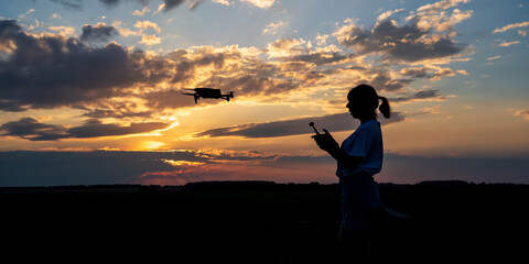 silhouette of woman controlling drone on sunset background