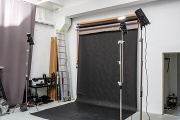 interior of bright space of photo studio with large black background and lighting equipment - Powered by Adobe