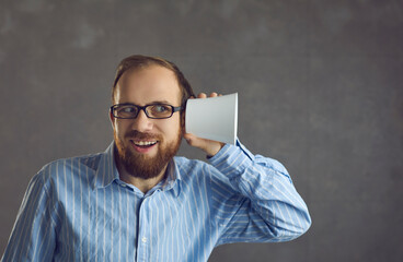 I can hear you. Funny happy curious man in glasses puts cup to ear, studio portrait. Boss listening...