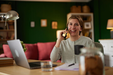Attractive young woman talking on the phone at home office