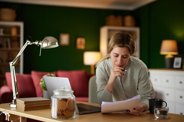 Mid adult woman examining her bank statement at home office