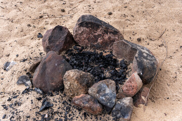 Fototapeta na wymiar an extinct bonfire of stones on the beach. An extinct campfire.