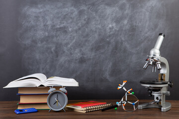 Back to school - books and microscope on the desk, Education concept. Blackboard background - 638805765