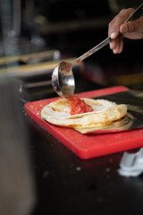 Malawach, a traditional Yemeni Jewish dish, being prepared at a food stall in Tel Aviv, Israel. It consists of flatbread made from puff pastry, topped here with tomato salsa.
