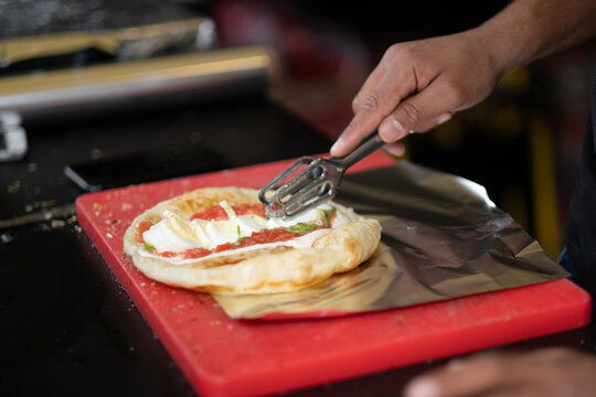 Sliced boiled egg is layered onto malawach, a staple of Yemeni Jewish cuisine that is not popular across all of Israel. This sandwich is being served up as street food in Tel Aviv.