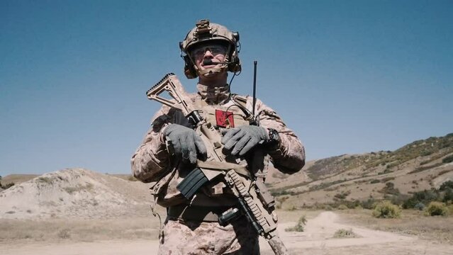 desert terrain. stands an armed soldier with a machine gun