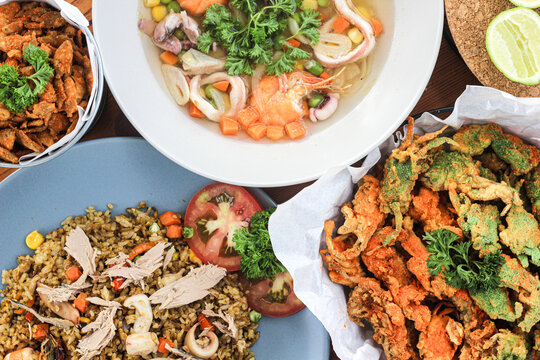 Close up photo of Assorted Seafood served on a wooden table. Asian Street Food, Seafood Fried Rice, Seafood Soup and Crispy Baby Fish dan Crispy baby Crab. Delicious Menu for seafood lovers.